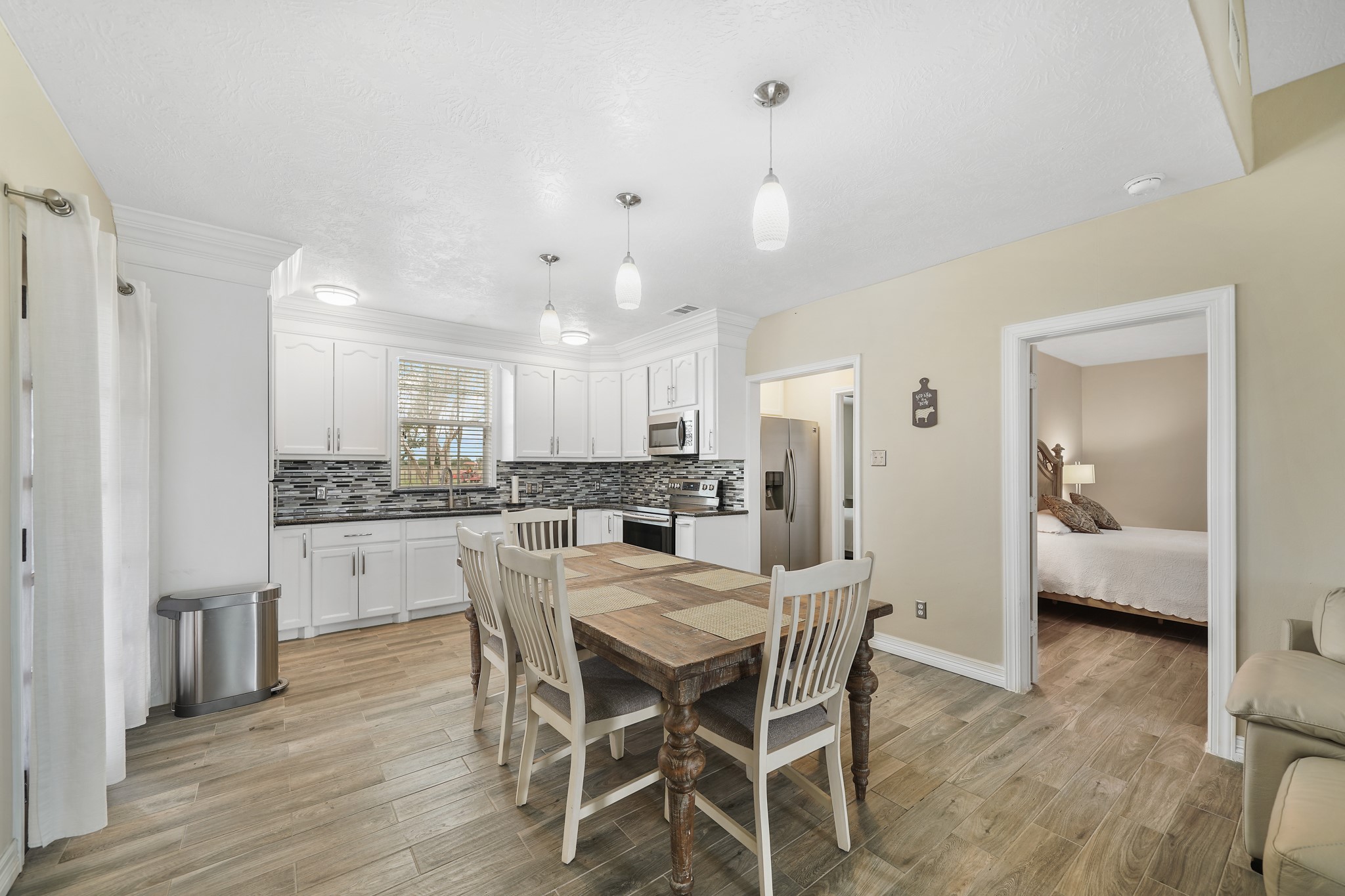 10507 Padon Road Needville, TX 77461 - Photo 30 of 48 a kitchen with stainless steel appliances kitchen island granite countertop a dining table chairs and white cabinets