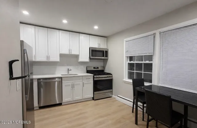 a kitchen with cabinets stainless steel appliances and a window