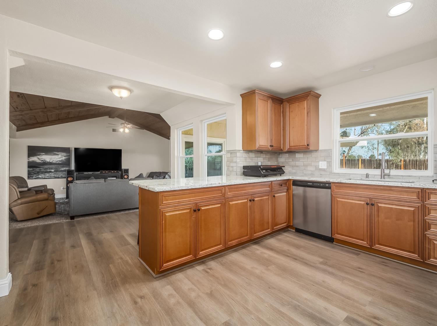 16181 Monreal Road Madera, CA 93636 - Photo 11 of 40 a large kitchen with stainless steel appliances granite countertop a stove a sink dishwasher and a microwave oven with wooden floor