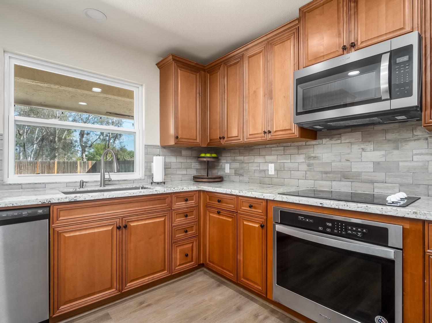 16181 Monreal Road Madera, CA 93636 - Photo 13 of 40 a kitchen with stainless steel appliances granite countertop wooden cabinets stove top oven and sink
