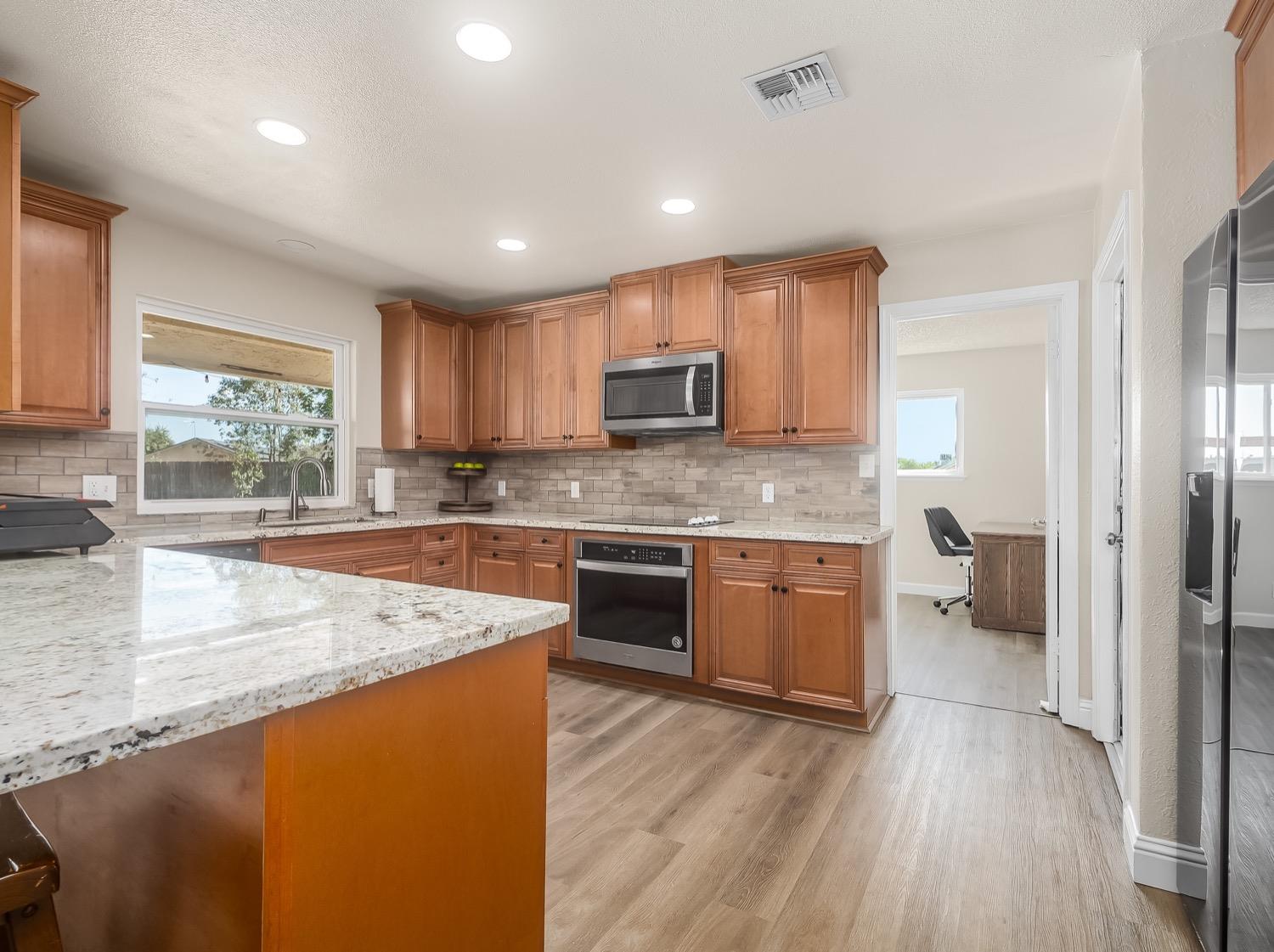 16181 Monreal Road Madera, CA 93636 - Photo 4 of 40 a kitchen with a refrigerator a sink dishwasher with a stove and cabinets