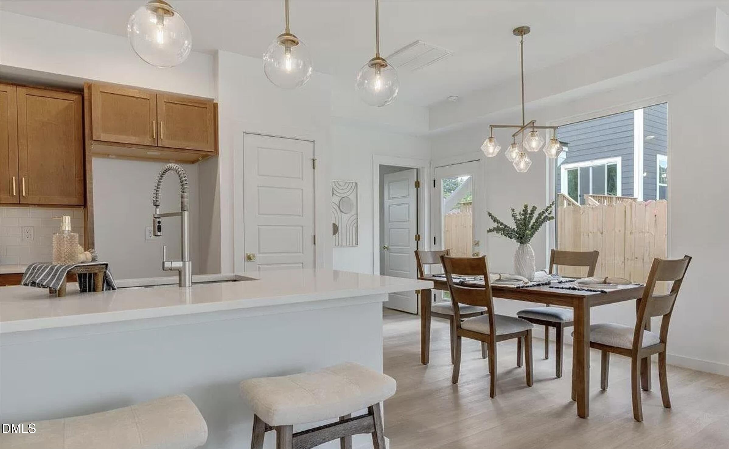 502 A Commonwealth Street Durham, NC 27703 - Photo 10 of 30 a kitchen with kitchen island a dining table chairs and white cabinets