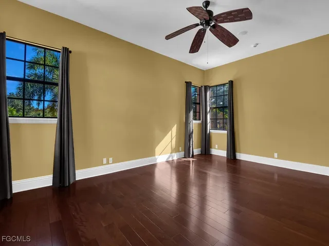 a view of an empty room with window and wooden floor