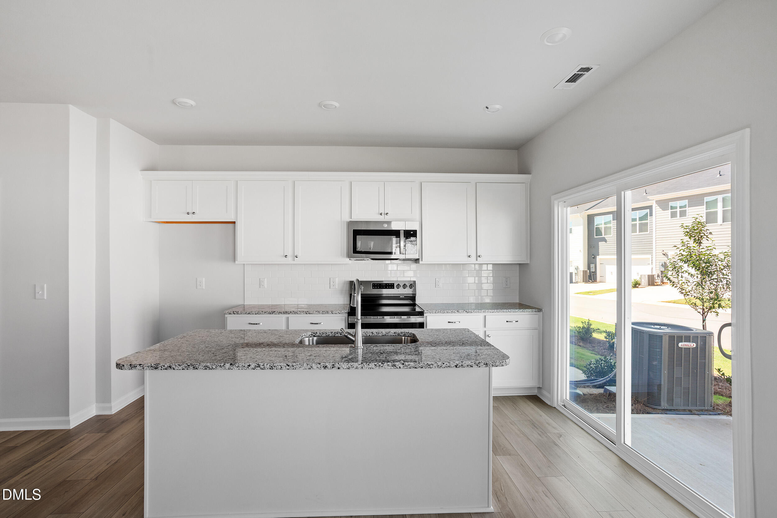 191 Powell Townes Way, Unit 319 Raleigh, NC 27603 - Photo 14 of 50 a kitchen with kitchen island granite countertop a stove top oven a sink and dishwasher