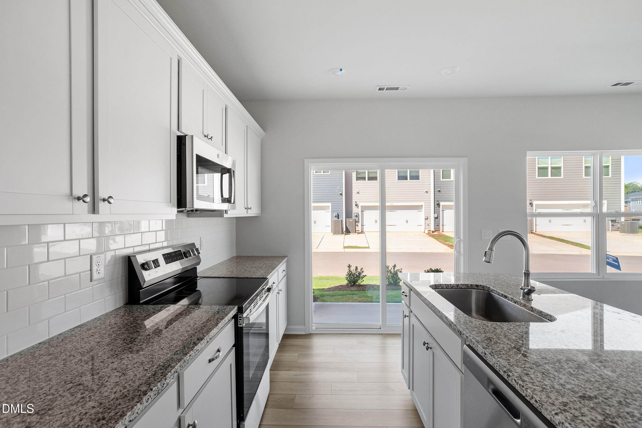 191 Powell Townes Way, Unit 319 Raleigh, NC 27603 - Photo 16 of 50 a kitchen with granite countertop a sink a stove and cabinets