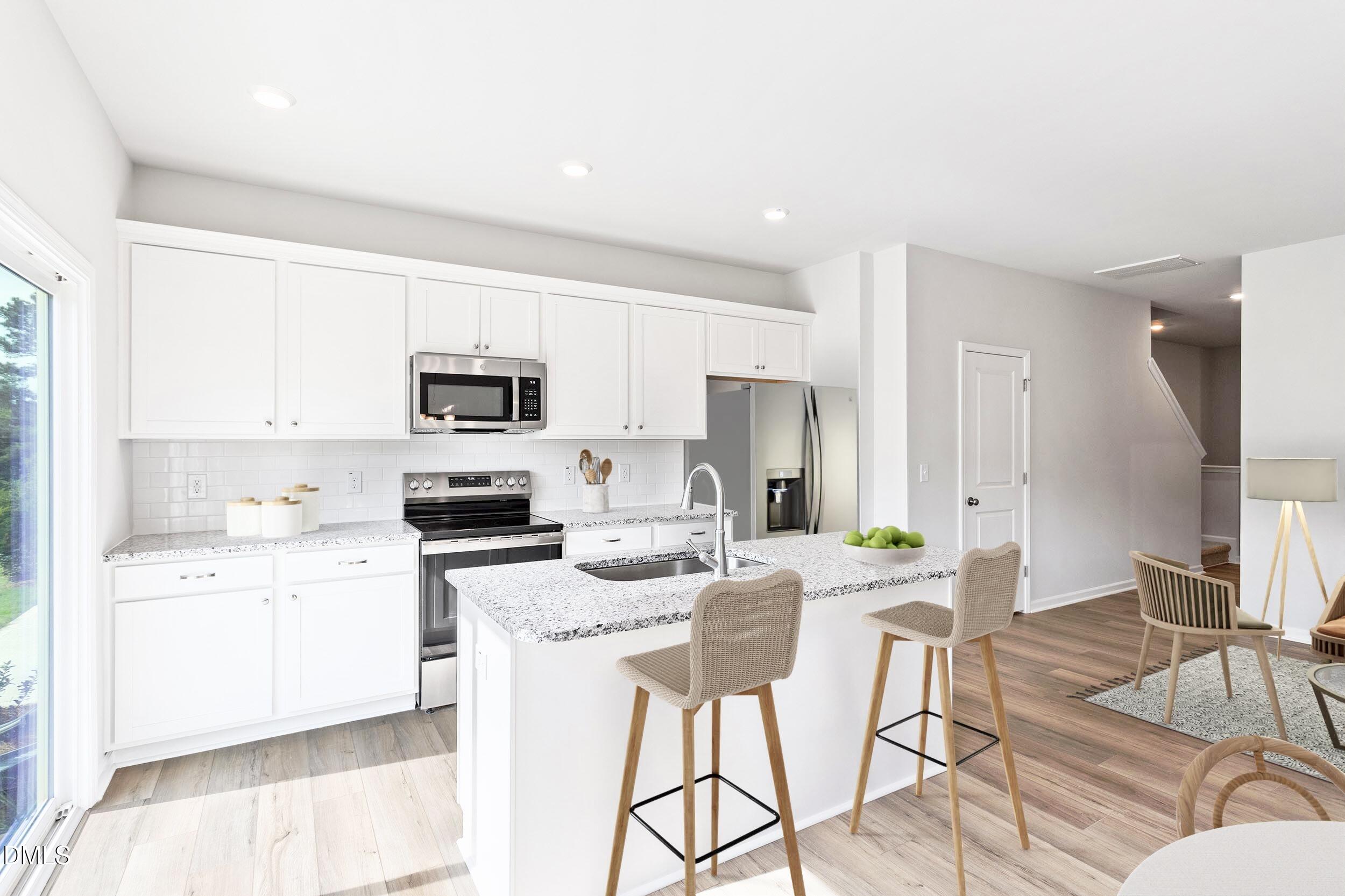 191 Powell Townes Way, Unit 319 Raleigh, NC 27603 - Photo 36 of 50 a kitchen with stainless steel appliances kitchen island granite countertop a refrigerator and microwave