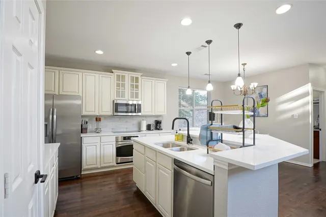 a kitchen with stainless steel appliances granite countertop a sink a stove a refrigerator and island with wooden floor