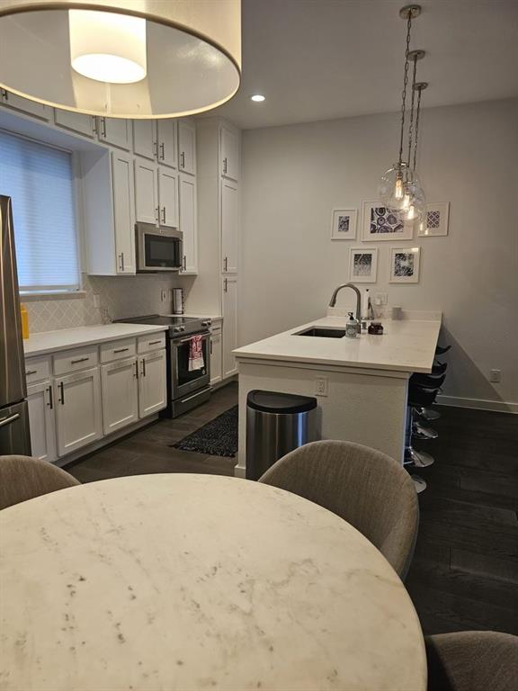6004 Hudson Street, Unit 104 Dallas, TX 75206 - Photo 5 of 16 a kitchen with kitchen island a stove a sink a refrigerator and chairs