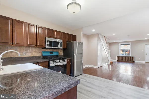 a kitchen with stainless steel appliances granite countertop a refrigerator a stove top oven a sink and dishwasher