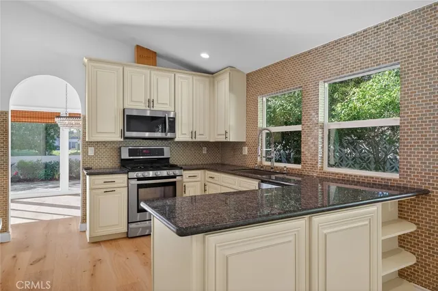 a kitchen with stainless steel appliances granite countertop a stove a sink and a microwave