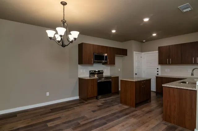 a kitchen with stainless steel appliances granite countertop wooden cabinets a stove top oven a sink and dishwasher