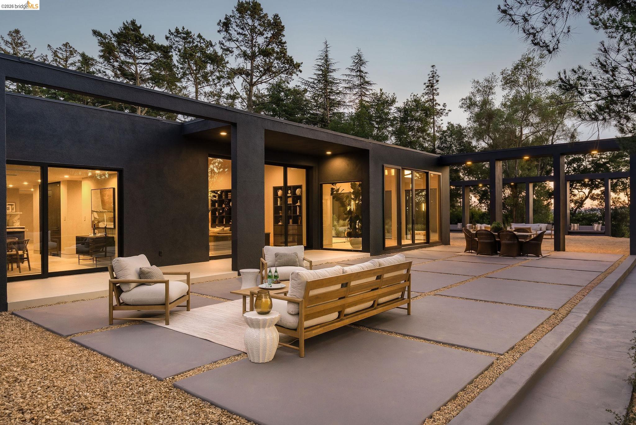 5645 Bacon Road Oakland, CA 94619 - Photo 3 of 94 Expansive outdoor patio featuring large concrete pavers, gravel accents, a structured pergola, and multiple floor-to-ceiling glass sliding doors