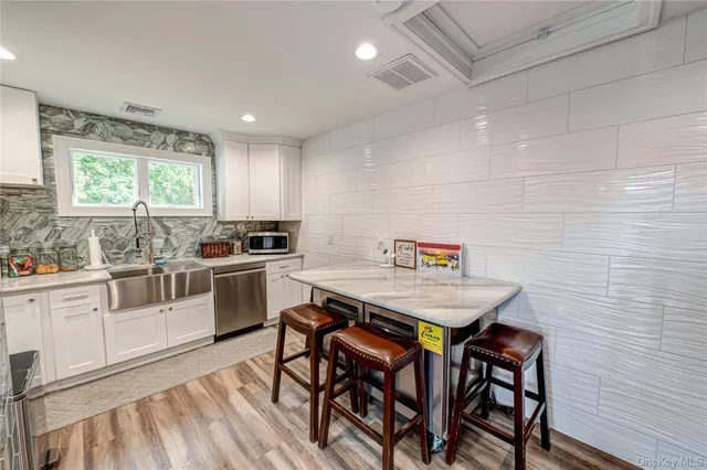 a kitchen with stainless steel appliances kitchen island granite countertop a table chairs sink and cabinets