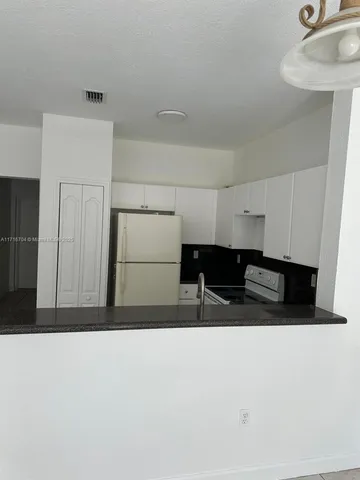 a living room with furniture and a refrigerator