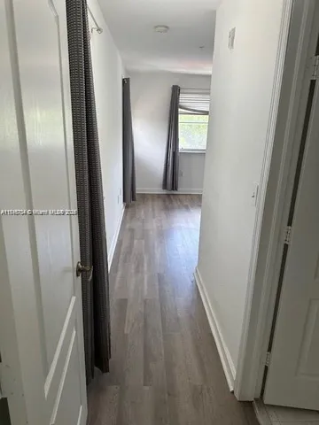 a view of hallway with window and wooden floor