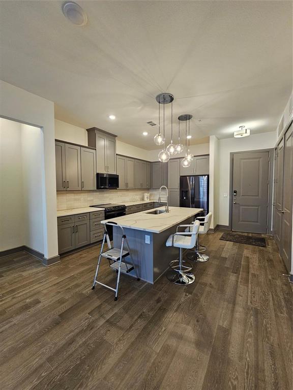 2700 Old Denton Road, Unit 3325 Carrollton, TX 75007 - Photo 6 of 6 Kitchen featuring wood-finish flooring, grey cabinetry, stainless steel appliances, and a central island with a waterfall countertop