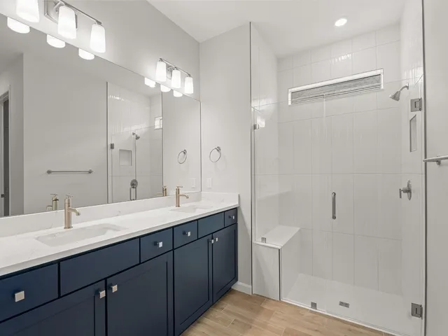 a bathroom with a double vanity sink mirror and shower