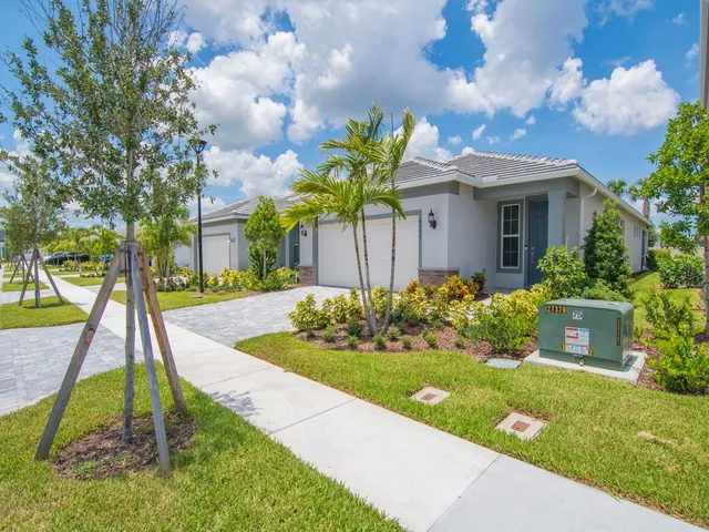 a front view of a house with a yard and potted plants