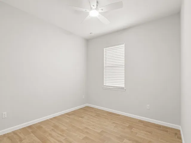 an empty room with a window and a fan