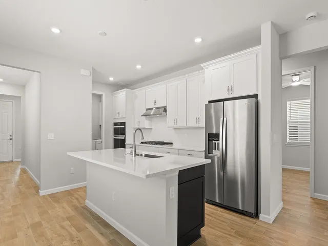 a kitchen with stainless steel appliances a refrigerator sink and white cabinets