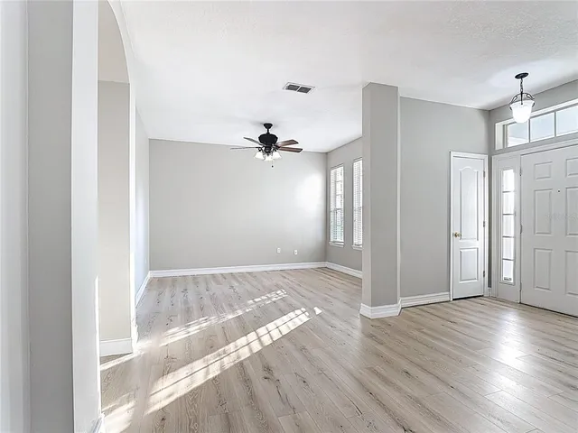 a view of empty room with wooden floor and fan