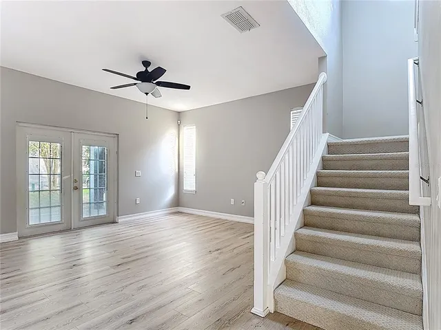 an empty room with wooden floor fan and windows
