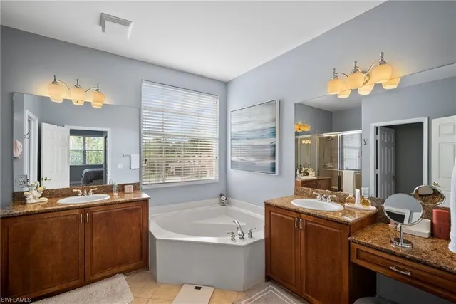 a bathroom with a tub double vanity sink and a mirror