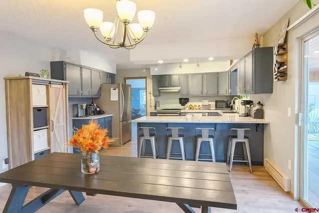 a kitchen with stainless steel appliances granite countertop a refrigerator a stove and white cabinets with wooden floors