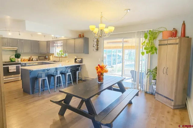 a dining room filled chandelier and wooden furniture