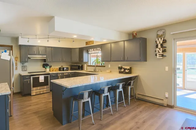 a kitchen with stainless steel appliances granite countertop a sink a stove and a refrigerator