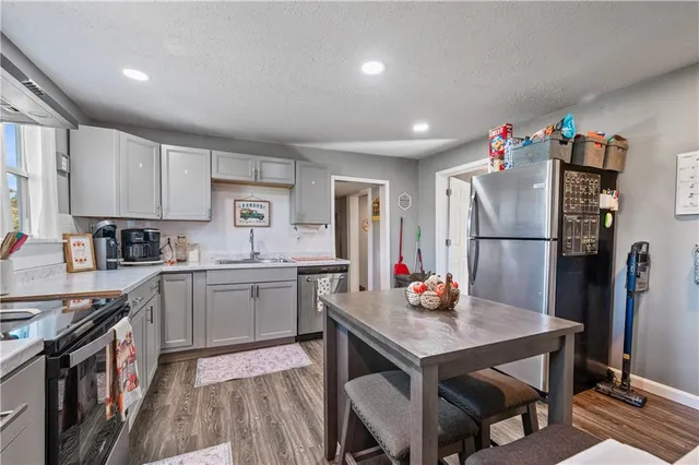 a kitchen with stainless steel appliances granite countertop a dining table chairs stove refrigerator and cabinets