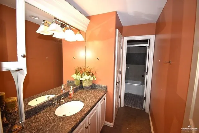 a bathroom with a granite countertop sink a mirror and a shower