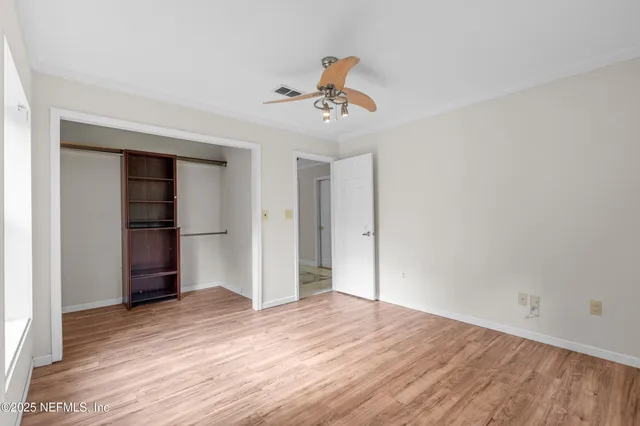 a view of empty room with wooden floor and ceiling fan