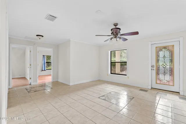 a view of an empty room with window and chandelier fan