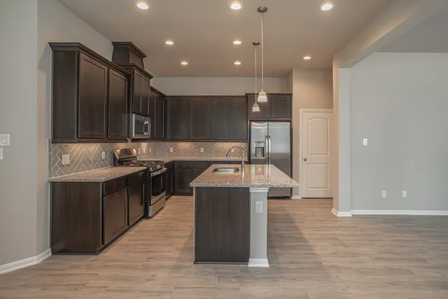 a kitchen with kitchen island stainless steel appliances a sink cabinets and wooden floor