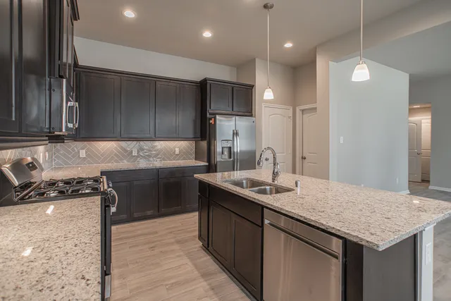 a kitchen with kitchen island granite countertop a sink a counter top space stainless steel appliances and cabinets