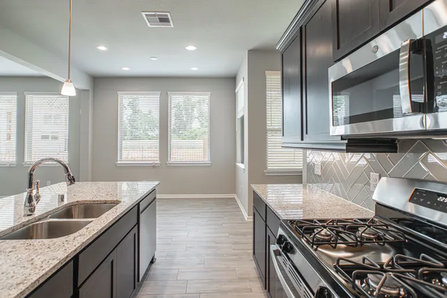 a kitchen with granite countertop a sink stove and cabinets