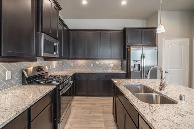 a kitchen that has a sink wooden cabinets and stainless steel appliances