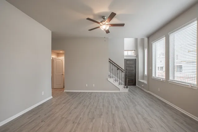 a view of an empty room with a window and wooden floor