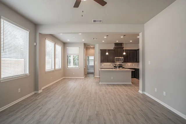 a view of large kitchen with kitchen island stainless steel appliances wooden floor and window