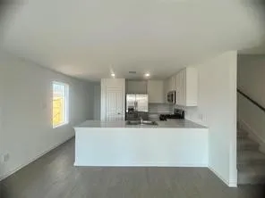 a large white kitchen with kitchen island a sink wooden floor and white cabinets