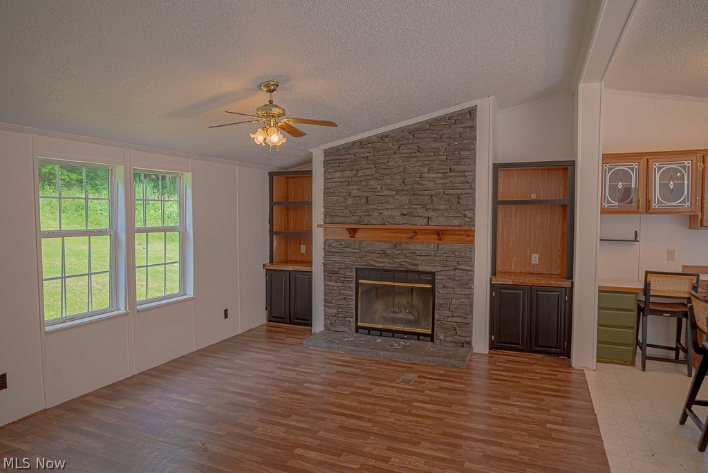 967 Buck Run Road Mineral Wells, WV 26150 - Photo 14 of 50 Living area featuring a stone fireplace with a wood mantle, wood-finish flooring, two large windows, built-in shelving, and a ceiling fan
