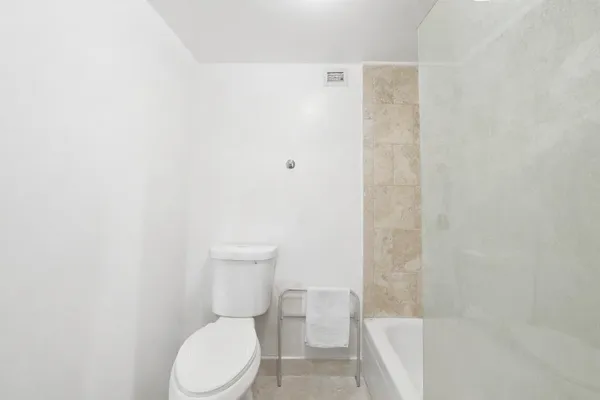 a white toilet sitting next to a shower