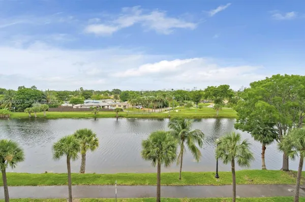 a view of a lake with a big yard and large trees