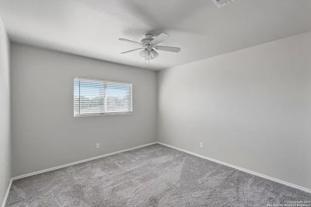an empty room with a window and a fan