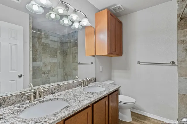 a bathroom with a granite countertop sink a toilet and a mirror
