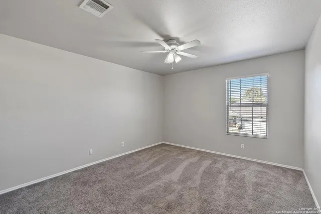 an empty room with a window and ceiling fan