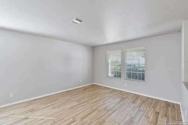 a view of an empty room with wooden floor and a window