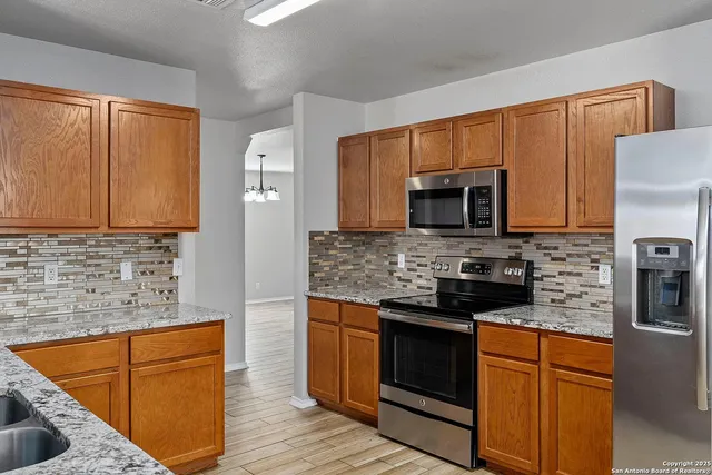 a kitchen with stainless steel appliances granite countertop wooden cabinets a stove a microwave and a sink