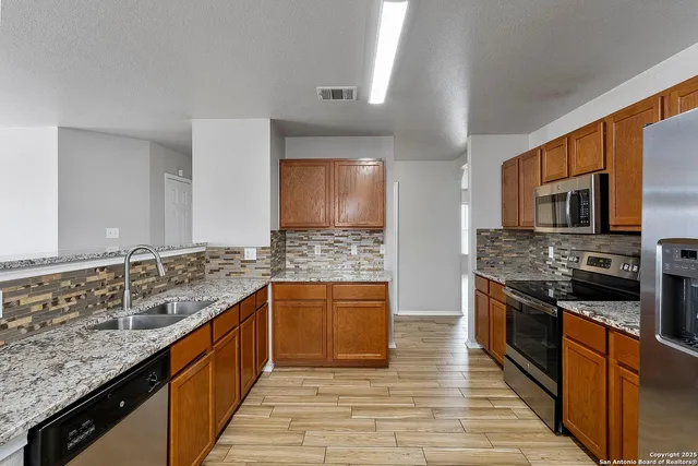 a large kitchen with stainless steel appliances granite countertop a stove a sink and a microwave